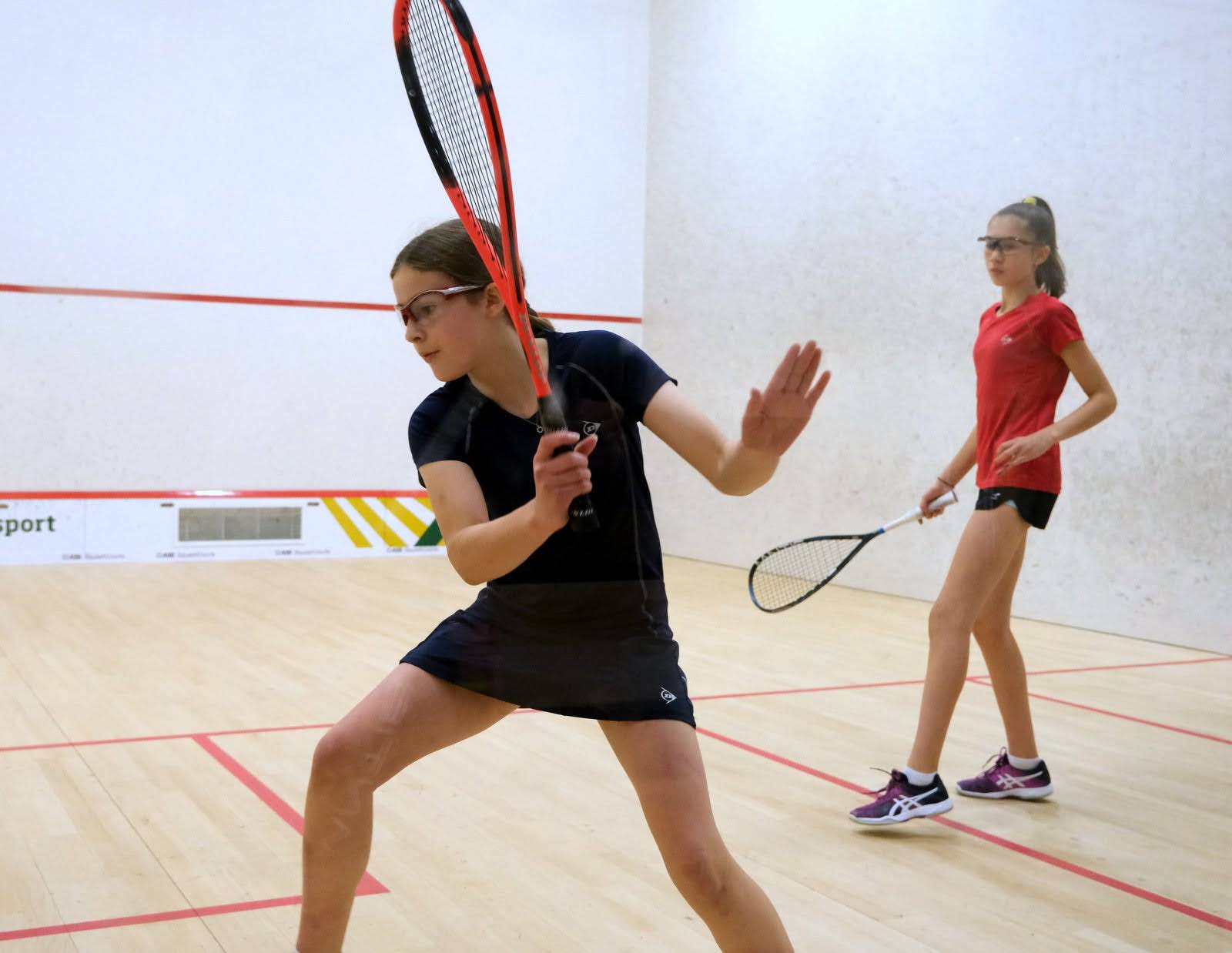Two junior players on court during a squash coaching session